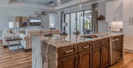 a large travertine marble kitchen island with living furniture in the background.